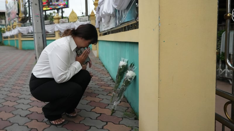A woman lays flowers and offers prayers at Debsirin Nonthaburi School, a day after the...